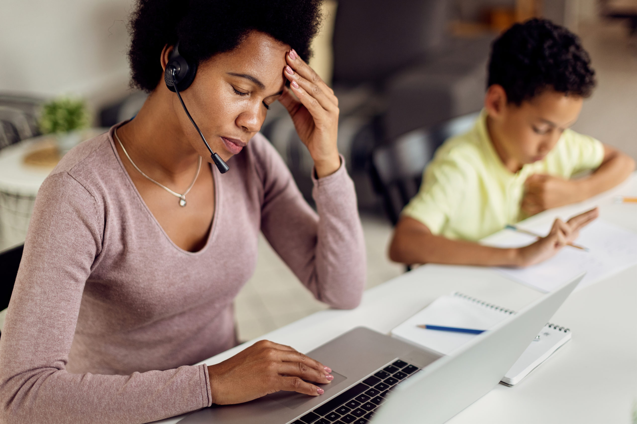 Woman working on computer while touching her head in pain.
